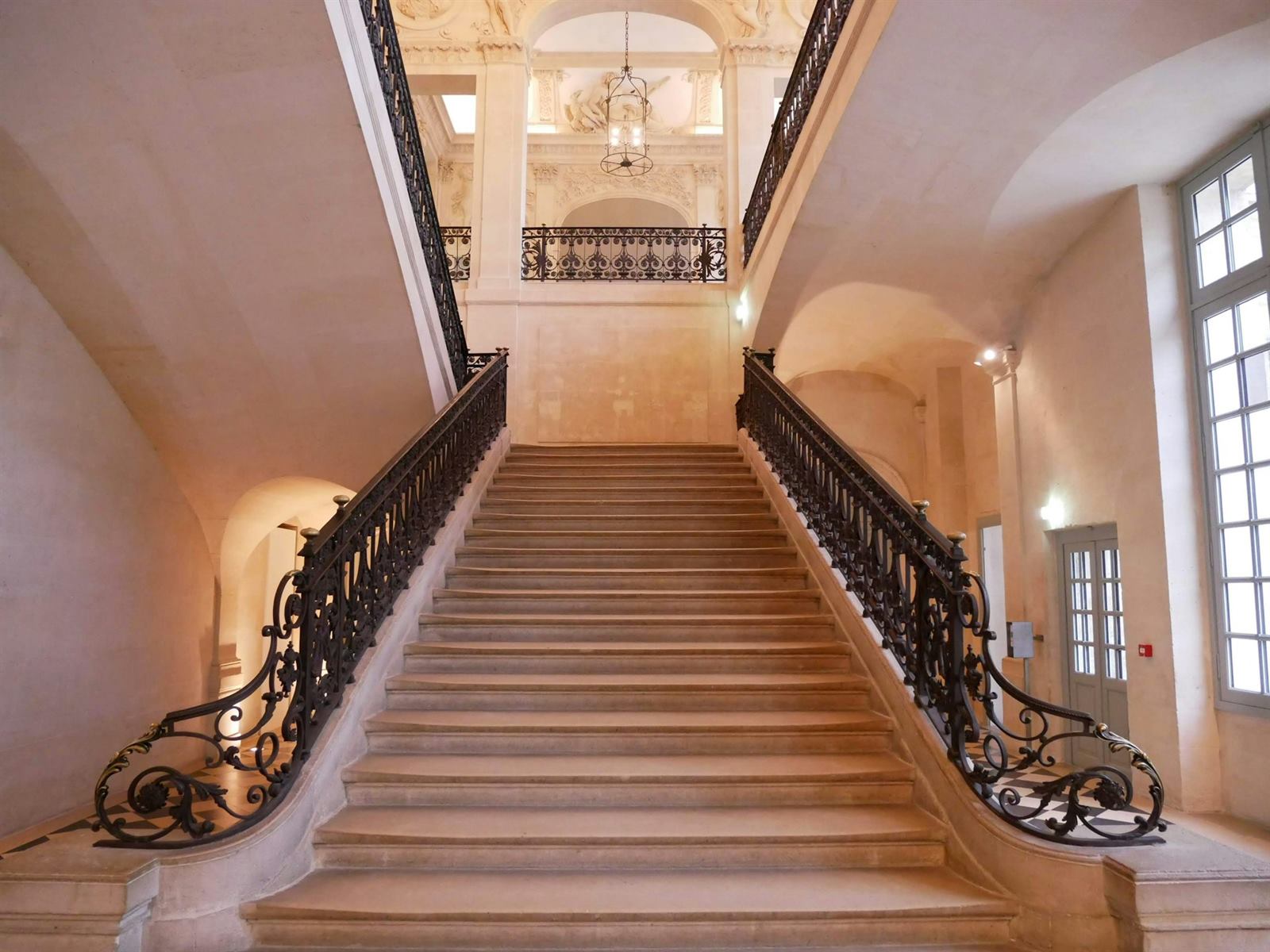 Escalier droit en pierre avec rampe en fer forgé, balustres et main courante visibles
