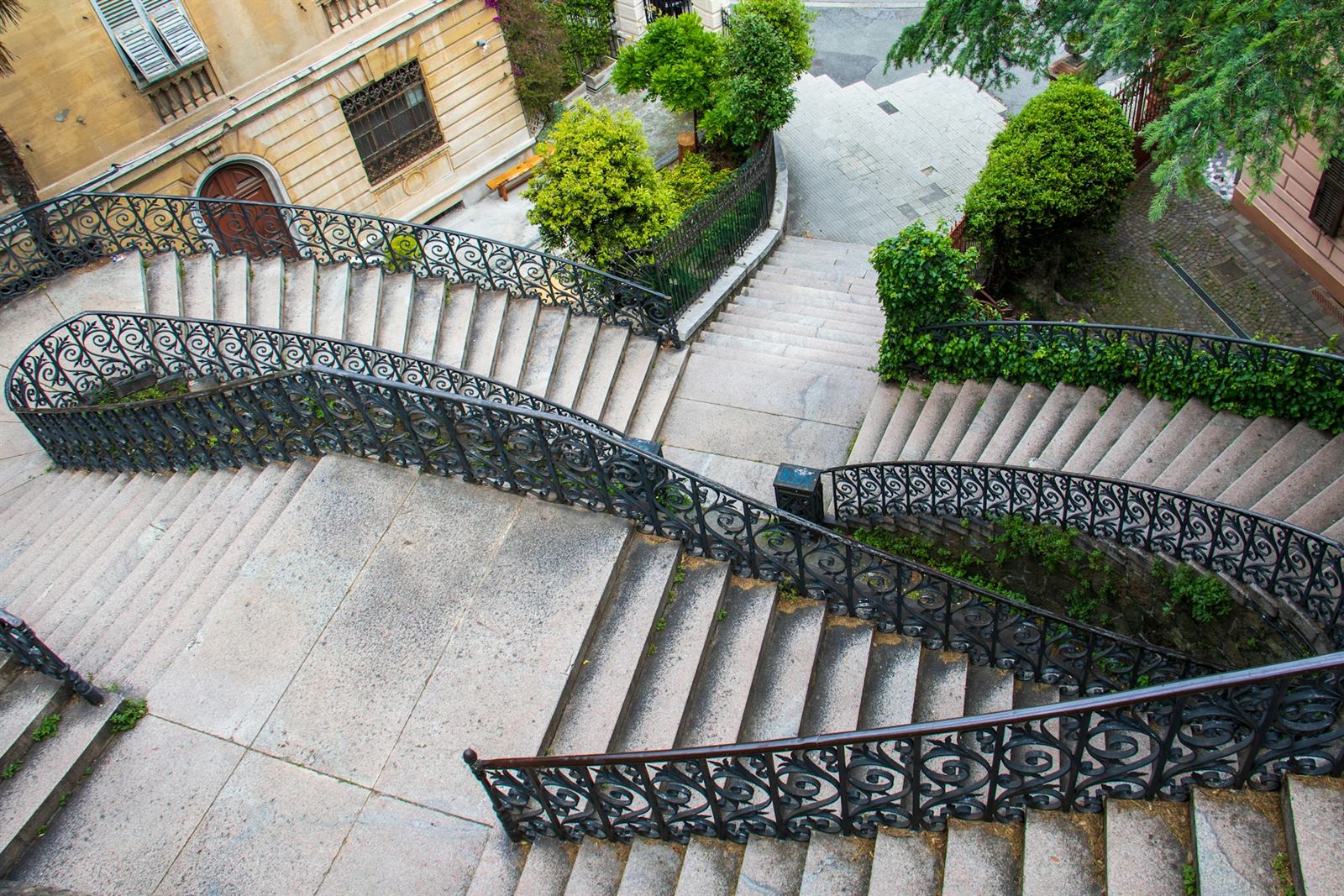 Escalier extérieur en pierre avec rampe en fer forgé devant une façade ancienne